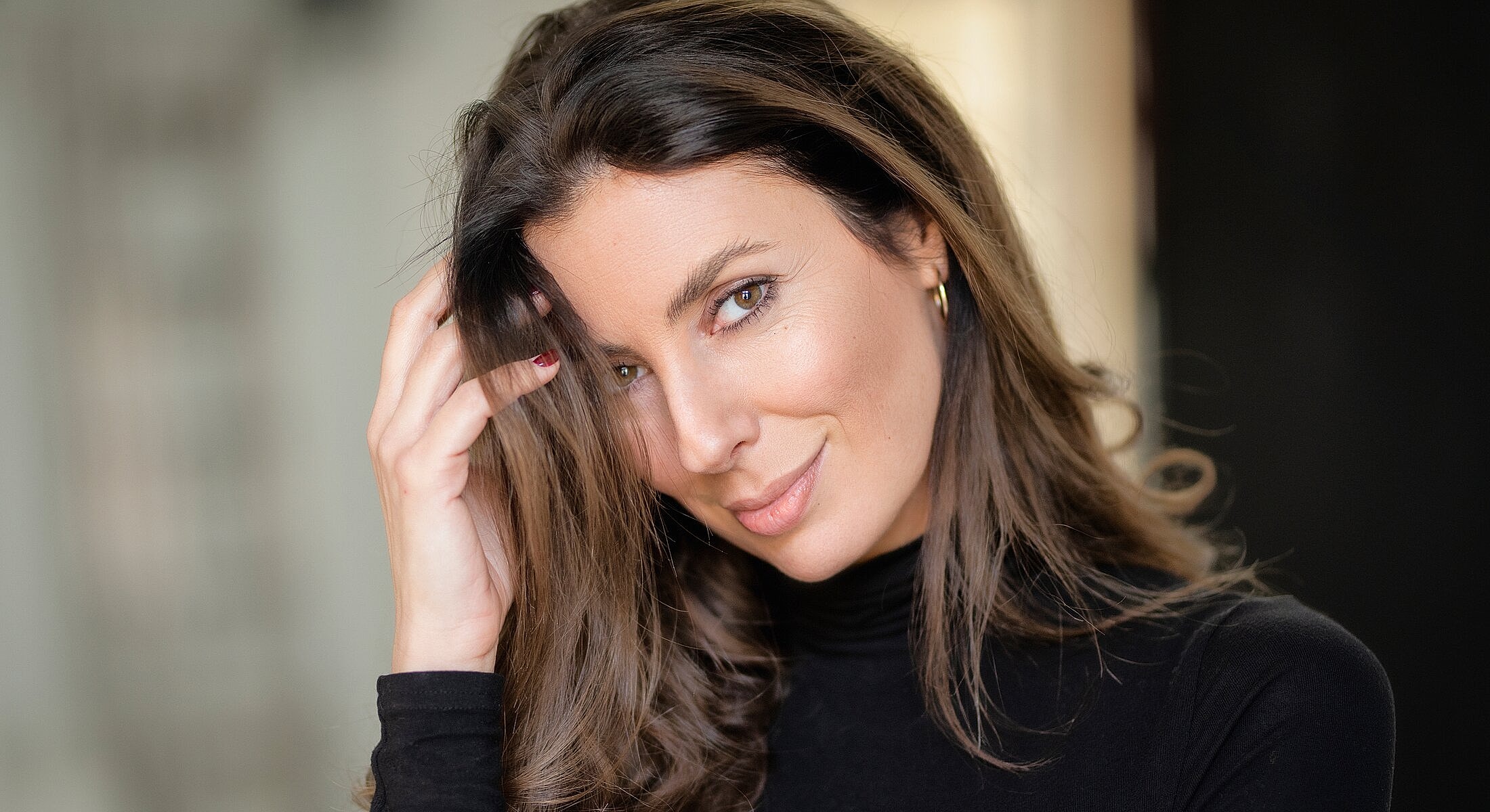 Woman with long hair smiling playfully.